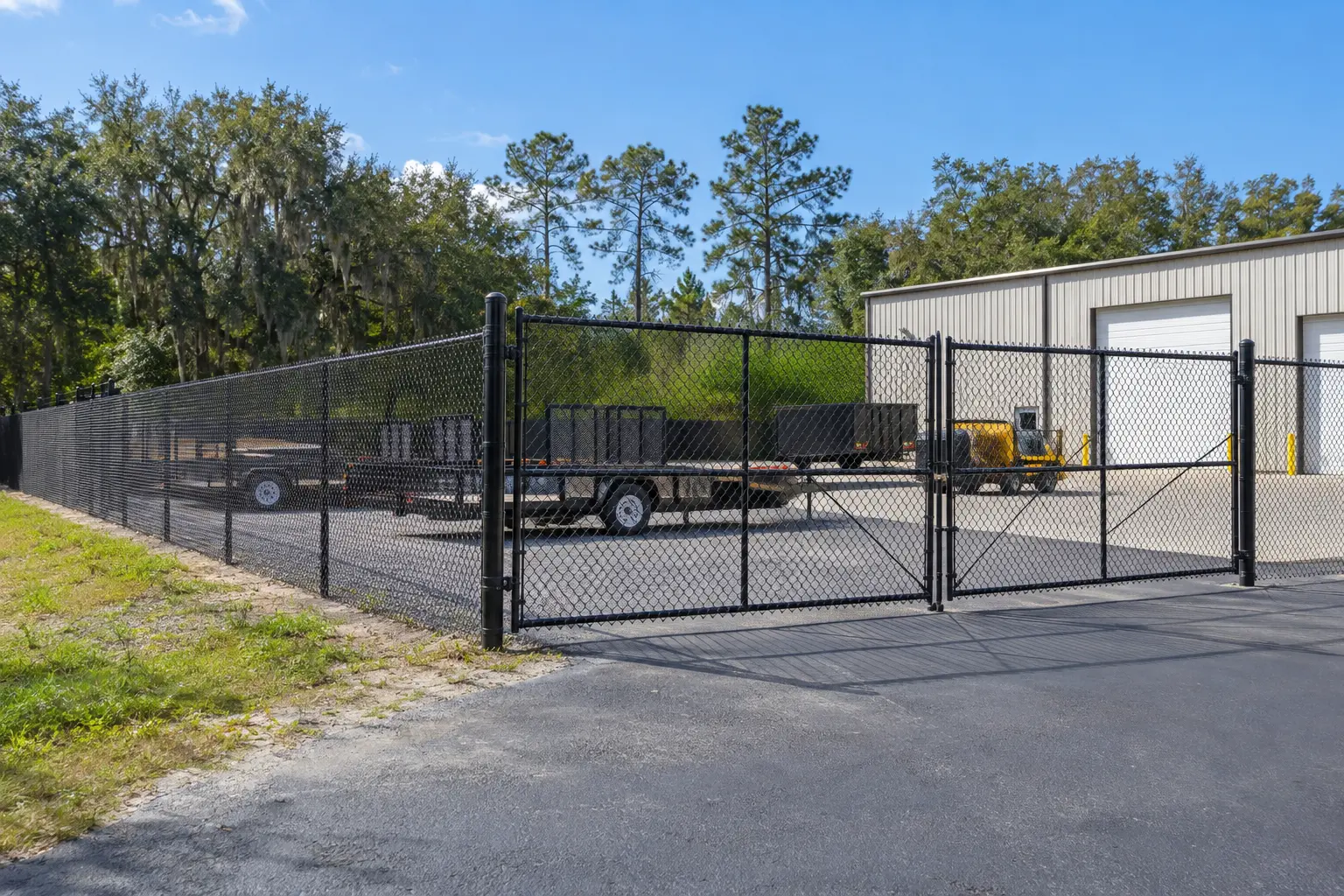 Black chain link security fence and vehicle gate around a local equipment yard