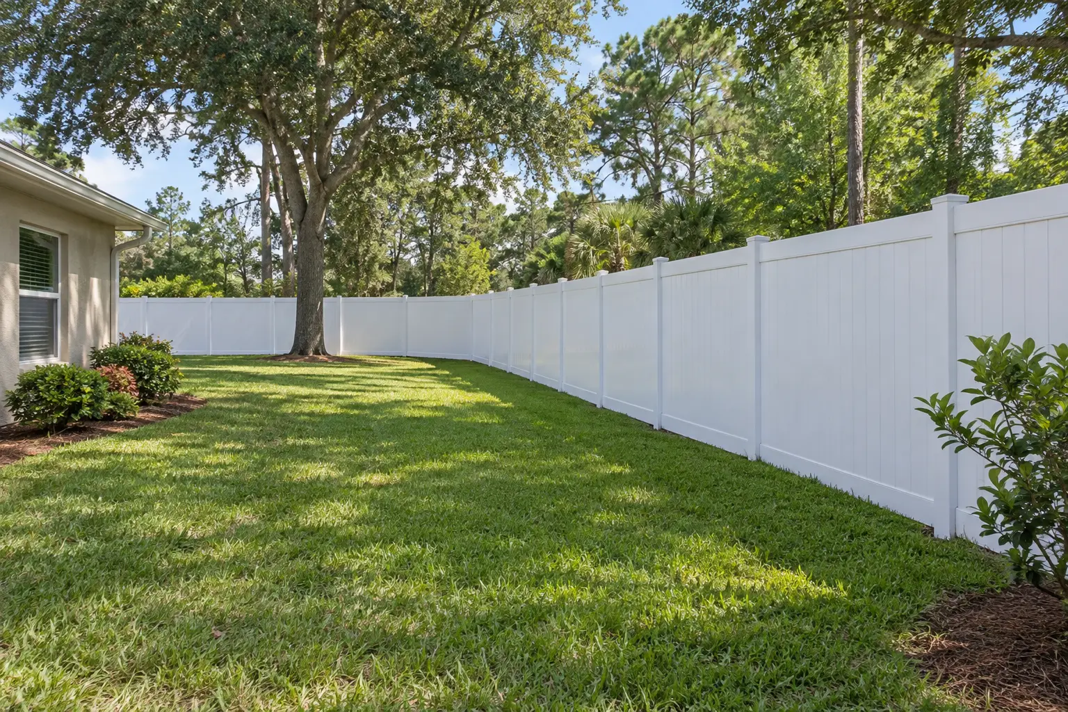 Long white vinyl privacy fence following a large local yard